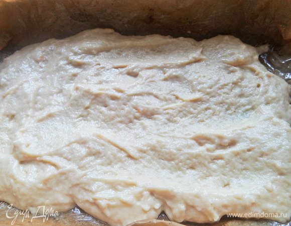 Распределить тесто (большую часть) по дну формы, которую застилаем пергаментом и смазываем.