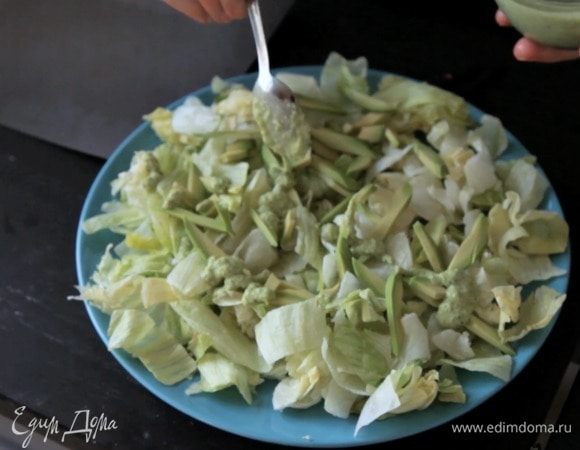 На тарелку выложить подушку из салатных листьев, сверху — авокадо и добавить часть заправки.