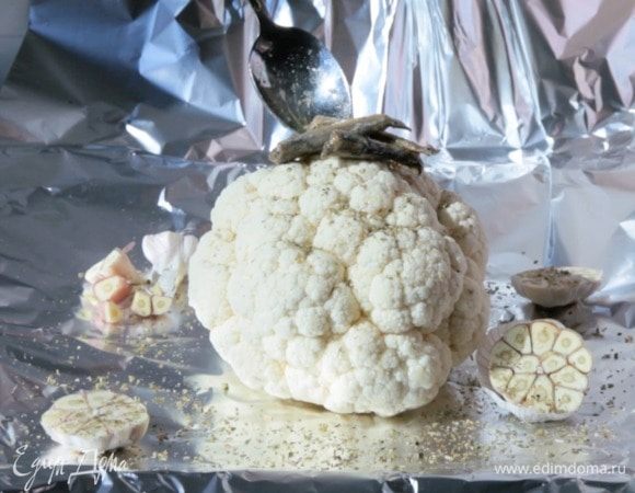 Сбоку — половинки головки чеснока. Посыпать розмарином, полить 2 ст. л. масла, выложить на капусту анчоусы и полить все еще раз маслом, но на этот раз от анчоусов.