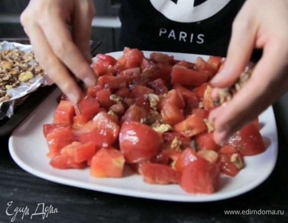 Заправить томаты, выложить на блюдо, посыпать орехами.