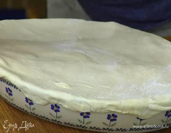 Предварительно размороженное слоеное тесто слегка раскатать, накрыть им форму с рыбой и луком, прижать края теста снаружи формы и срезать лишнее тесто — должна получиться плотная крышечка.