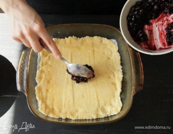 Застелить форму пекарской бумагой и равномерно распределить тесто. Сверху смазать джемом.