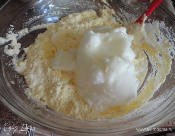В желтки добавить миндальную эссенцию и протертый творог. Перемешать. Белки частями ввести в творожную массу.