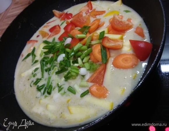 Влить оставшееся молоко и бульон, добавить перец, морковь и 2/3 зеленого лука. Довести до кипения, уменьшить огонь и добавить кабачок. Варить 4-5 минут. 