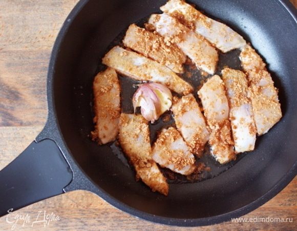 Запанировать брусочки судака в отрубных крошках. В горячем растительном масле слегка обжарить неочищенный зубок чеснока до появления аромата и тут же обжарить рыбное филе. Лучше это сделать партиями, чтобы не повредить брусочки.