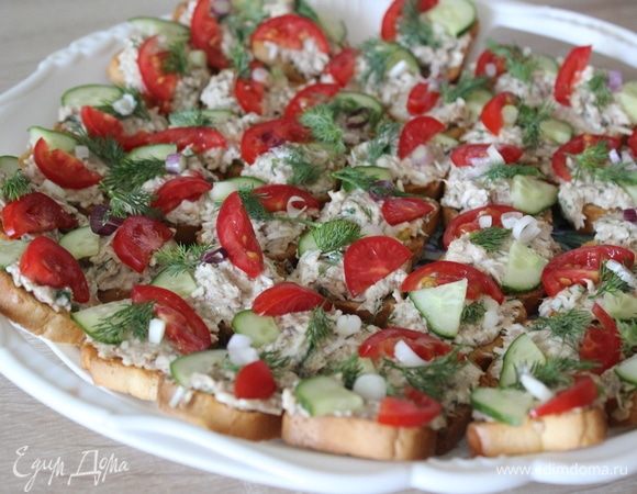 На каждое канапе положить по маленькому ломтику помидора и огурца. Украсить зеленью.