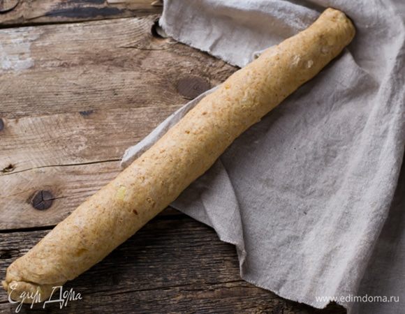 Поднявшееся тесто снова вымесить и раскатать в виде прямоугольника на посыпанной мукой поверхности. Скатать прямоугольник в длинную трубку, края прижать.