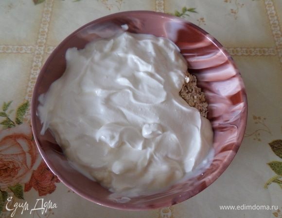 Подготавливаем продукты. В чашку насыпаем овсяные хлопья. Добавляем сметану. Перемешиваем и оставляем на 10-15 минут.