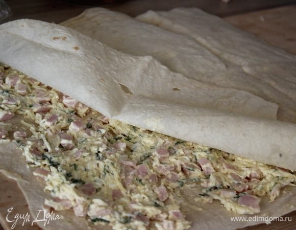 Лист лаваша разрезать на 2 части.
На один лист разложить половину начинки. Накрыть вторым листом.