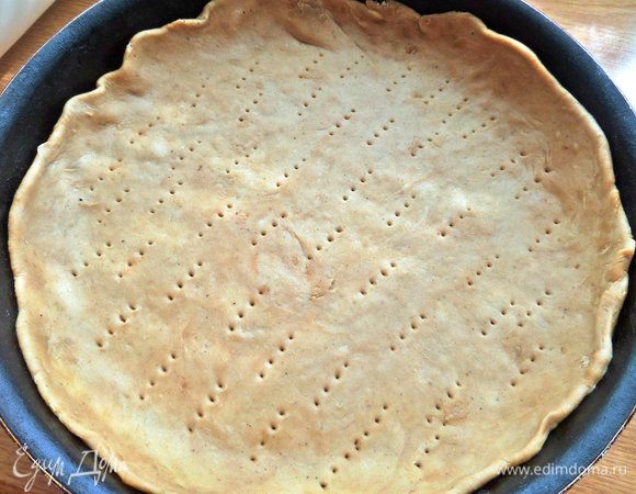 Эластичный пласт теста перенести в форму, наколоть дно вилкой.