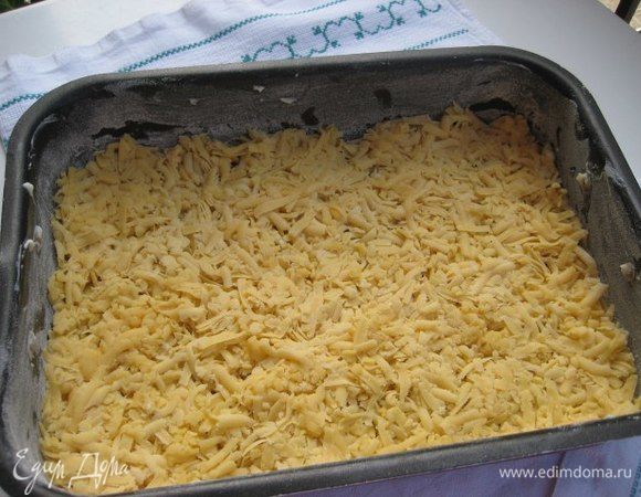 Форму для выпечки (25*35) смазать маслом, по желанию застелить бумагой для выпечки. Половину теста натереть на терке, распределить по форме, прижать немного руками.