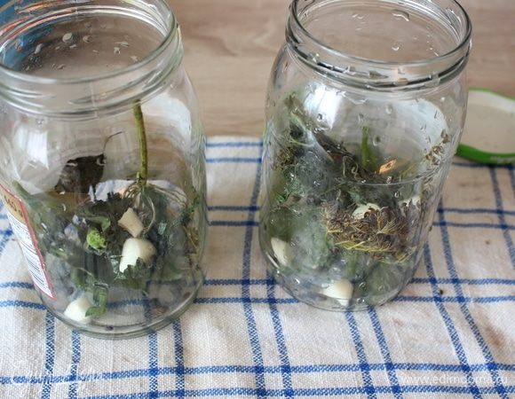 С огурцов срезать кончики, замочить на три часа в холодной воде. В банки положить по паре зонтиков укропа и зубчиков чеснока, по 3 листа вишни и черной смородины, по половине листа хрена, по 7 горошин черного перца.