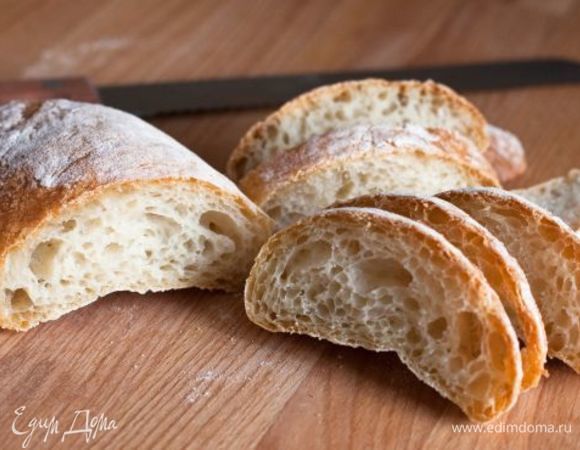 Чиабатту нарезаем на ломтики 1 см толщиной. Смазываем каждый кусочек с обеих сторон оливковым маслом. Выкладываем ломтики на противень, застеленный пекарской бумагой и отправляем в духовку, разогретую до 180°С. Подсушиваем по 5 минут с каждой стороны.