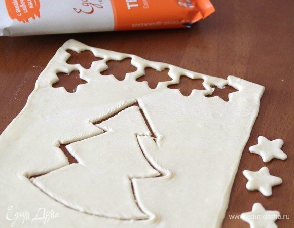 Слоеное дрожжевое тесто раскатать до толщины 0,5 см. С помощью формочек вырезать звездочки, елку вырезать с помощью ножа.
