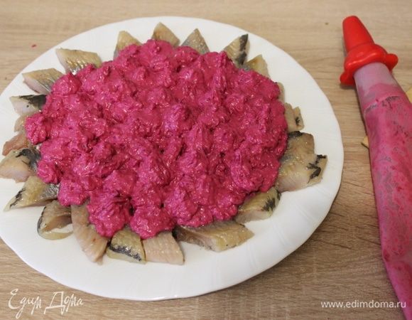 Наполнить кондитерский мешок свекольным крем-соусом. Выложить крем-соус поверх ломтиков сельди.