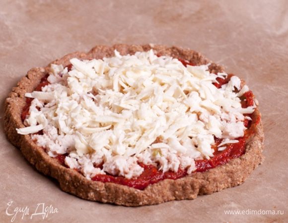 Куриный фарш посолить и поперчить. Выложить на основу. Сыр натереть на крупной терке. Посыпать им пиццу.