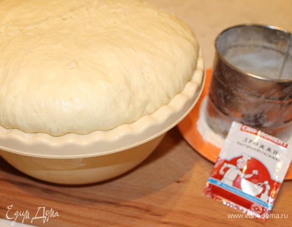 Готовим дрожжевое тесто для пирога. Все продукты необходимо выложить на стол, чтобы они согрелись до комнатной температуры.
Муку просейте дважды, она обогатится кислородом, и дрожжи, которые вы добавите к муке, потом оживут и задышат полной грудью. 
В чаше для замеса теста венчиком разбейте яйца с сахаром и солью, добавьте к яичной смеси кефир, растительное масло масло, перемешайте и постепенно вмешивайте муку. Тесто должно у вас получиться вязким, липким и, поэтому, количество муки может меняться, как в меньшую сторону, так и в большую. В рецепте указано среднее значение. Когда вы вмешали необходимое количество муки, выложите тесто на стол, припудрив его мукой. И месите его руками в течение 10 минут. Тесто из липкого будет становиться более послушным и собираться в ком. 
Готовый шар теста верните в миску, припудрите сверху мукой и накройте слегка влажным полотенцем или крышкой. Оставьте тесто в теплом месте для подъема, сделав одну осадку. На подъем теста вам потребуется от двух до двух с половиной часов.