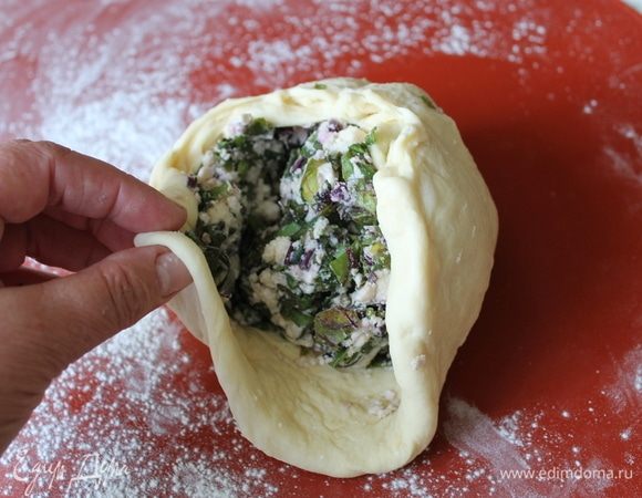 Отдохнувшее тесто пальчиками аккуратно расплющите в небольшую лепешку, положите посередине начинку и, поднимая края теста, закройте ее полностью.