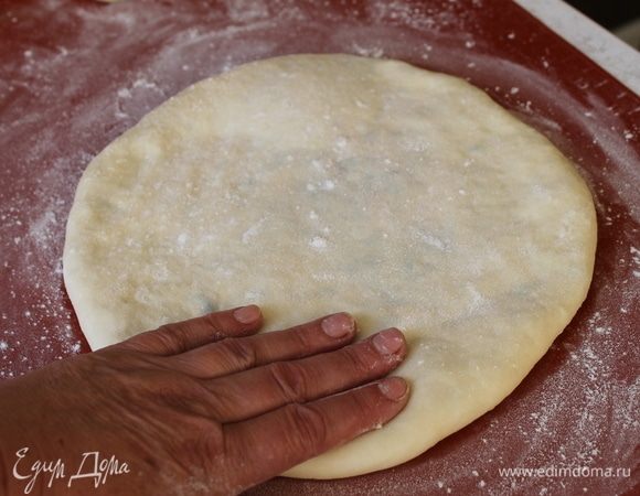 И очень бережно, слегка придавливая пальчиками, формируйте круглый пирог, распределяя равномерно начинку от середины к краям. Чтобы начинка расположилась между тестом посередине, переверните лепешку несколько раз, растягивая равномерно тесто с каждой стороны. 