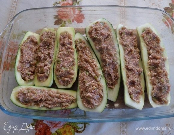 В глубокую форму для запекания выкладываем «лодочки» кабачков. Начиняем их подготовленным фаршем.