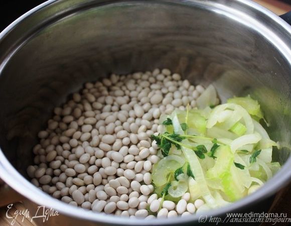 Заранее отварите до полуготовности белую фасоль вместе с сельдереем, тимьяном и обжаренным на оливковом масле луком (на указанное количество фасоли возьмите 1 луковицу). Фасоль лучше замочить на 6-8 часов, тогда ее достаточно варить в течение 40-50 минут (без замачивания нужно будет варить 1,5-2 часа).