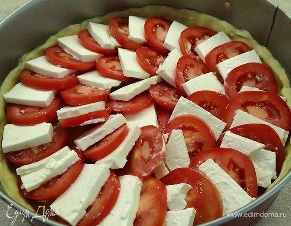 Достаем форму с тестом и выкладываем брынзу и помидоры по кругу. Поливаем сверху заливкой.