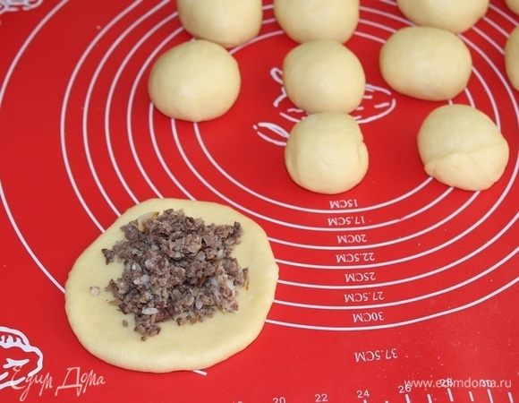 Каждый кусочек теста немного разминаем руками в пласт и выкладываем начинку. Смазываем пирожки желтком, смешанным с молоком.