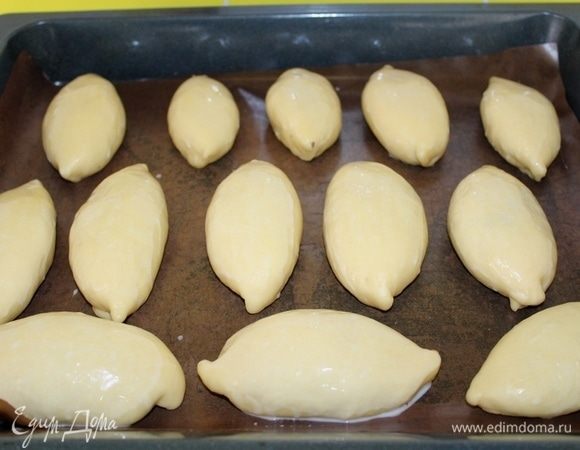 Формируем продолговатый пирожок и защипываем края, выкладываем на противень, выстланный пергаментом для выпечки. Оставить пирожки для расстойки на 15 минут, накрыв полотенцем. Затем смазать смесью яйца с молоком.