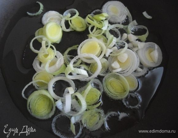 Готовим ризотто. Разогреть масло в сковородке, добавить нарезанный лук-порей. У меня молоденький с огорода, если у вас большой, хватит и половинки головки. Обжарить. Через минуту добавить нарезанный мелко чеснок. Перемешать. Огонь средний. Готовим минуту.