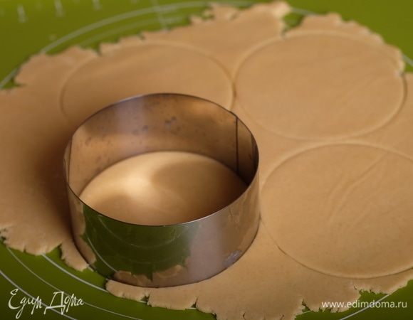 Раскатать тесто (сверху положить пергамент, так тесто не будет прилипать к скалке) до толщины 2-3 мм и круглыми вырубками вырезать круги, диаметром на 2-3 см больше, чем внутренний диаметр формочек для тарталеток.