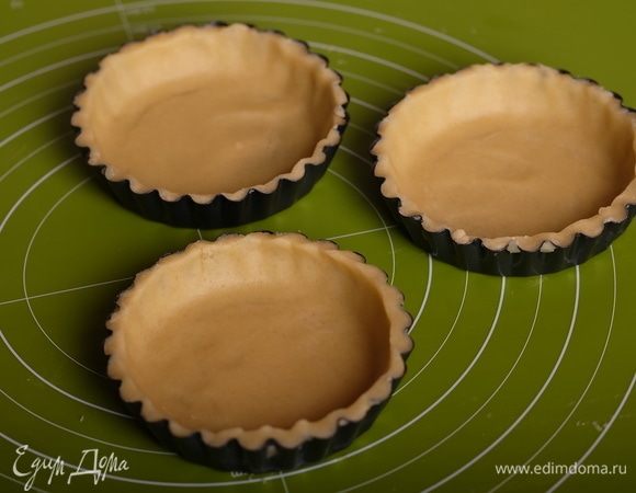 Далее уложить круги в формочки для тарталеток, аккуратно прижимая ко дну и краям формы. Излишки теста обрезать. Поместить формы с тестом в холодильник еще на час. За это время хорошо разогреть духовку до 180°С.