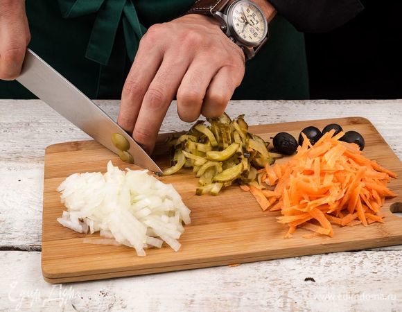 Нарежьте полукольцами репчатый лук и натрите на терке морковь. Соленый огурец нарежьте кубиками, а маслины без косточек — колечками.