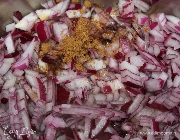 В кастрюлю с толстым дном налить оливкового масла, высыпать мелко порезанный лук, сверху посыпать тростниковым (коричневым) сахаром для карамелизации лука, накрыть крышкой и тушить периодически помешивая на медленном огне 7 минут.