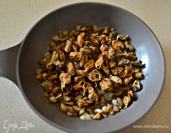 Добавить мидии (предварительно размороженные и промытые под холодной проточной водой). Тушить все вместе в течение 2-3 мин.