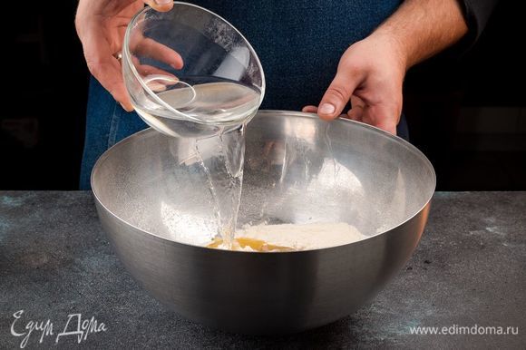 Приготовьте тесто для пиццы. Для этого просейте муку. Добавьте в нее сухие дрожжи, масло, соль и сахар. Все хорошо перемешайте, добавьте 135 мл теплой воды. Перемешайте, Замесите тесто, добавляя постепенно оставшуюся муку. Вымешивайте, пока тесто не перестанет липнуть к рукам. Накройте тесто полотняной салфеткой и поставьте в теплое место на 45 минут.