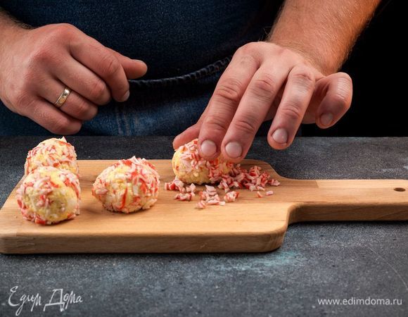 Из полученной массы сформируйте шарики. Красные слайсы крабового мяса измельчите.