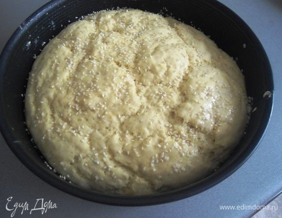 Тесто вырастает не сильно из-за использования кукурузной муки. Аккуратно смазать или лучше сбрызнуть верх теста водой и присыпать кунжутом.