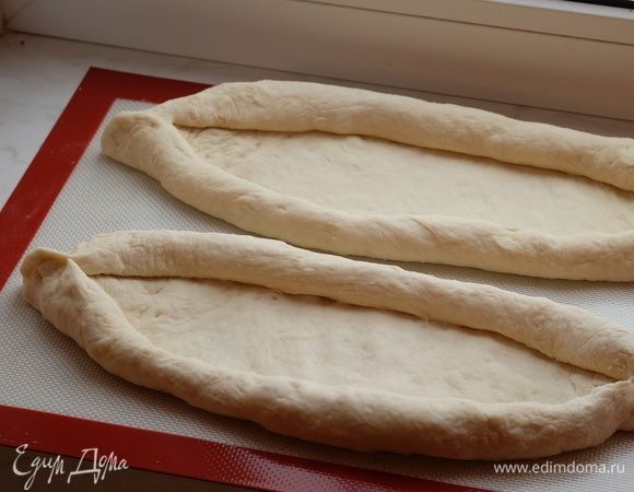 Из каждой части руками сформировать овальную лепешку. Края широкой части лепешки свернуть валиком к центру. Края защипнуть. Далее руками растянуть валики от центра, чтобы внутри образовалось место для начинки.