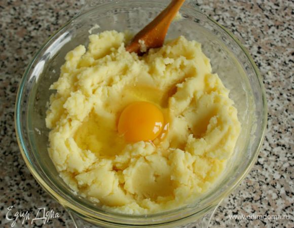 Слить воду из кастрюли с картофелем, а горячий картофель размять или пропустить через мясорубку, как указано в рецепте, смешать с 50 г сливочного масла, крахмалом, яйцом и посолить. По желанию можно приправить тертым мускатным орехом.
Разогреть духовку до 200°С.