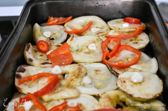 Выложим баклажаны и кабачки в форму для запекания слоями. Сверху — нарезанный болгарский перец и чеснок. Сбрызнем овощи бальзамическим уксусом.