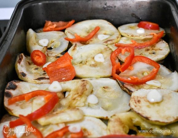 Выложим баклажаны и кабачки в форму для запекания слоями. Сверху — нарезанный болгарский перец и чеснок. Сбрызнем овощи бальзамическим уксусом.