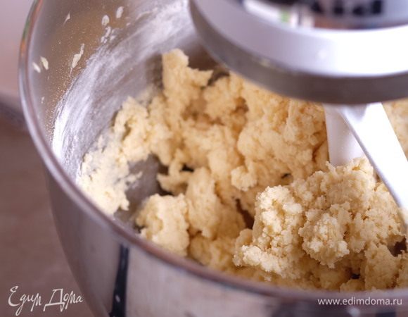 Перемешиваем на средней скорости миксера насадкой «лопатка» или на ручном миксере «спиральки». Долго вымешивать нельзя — как только компоненты соединились и стали образовывать неоднородные «комки» — выключаем миксер. Чем дольше вымешивать песочное тесто, тем менее рассыпчатым оно будет после выпечки.