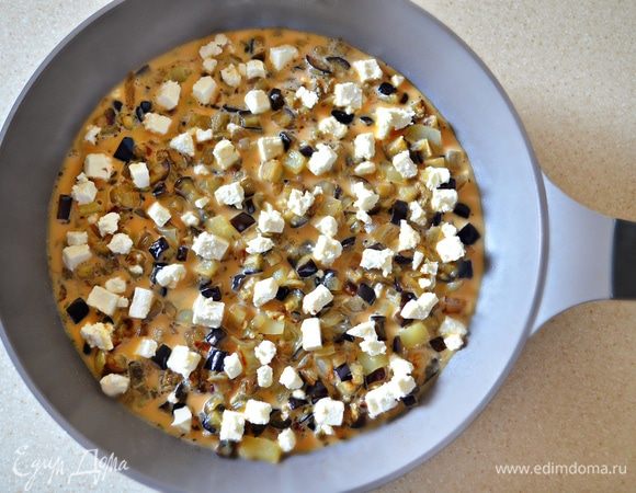 Залейте яичной смесью и посыпьте брынзой или любым рассольным сыром. Готовьте на маленьком огне под крышкой до готовности (примерно в течение 15 мин).  