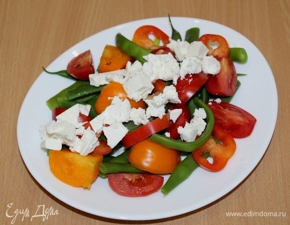 Заправить фасоль и выложить на блюдо. Сверху положить помидоры, сладкий перец и раскрошенную фету. 