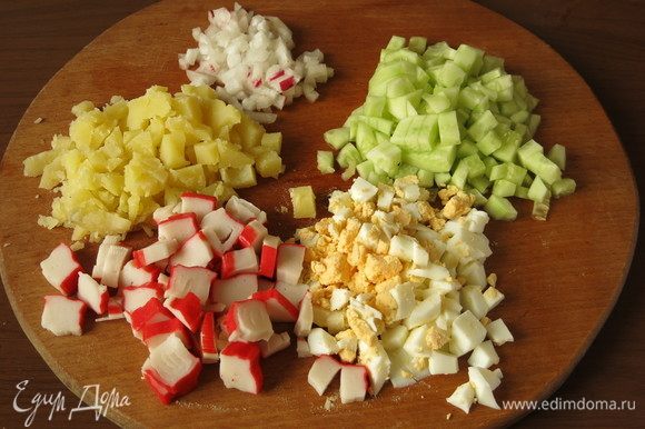 Нарезать яйца и картофель отварной кубиками, свежие огурцы и редис — мелкими кубиками, палочки крабовые — шайбочками.