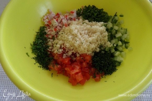 В чашку выкладываем нарезанные овощи, крабовые палочки, зелень, кускус и измельченный зубчик чеснока. Солим по вкусу.