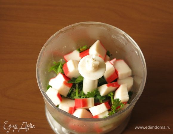 Нарезаем крабовые палочки, кладем в процессор. К палочкам кладем петрушку, предпочтительнее использовать веточки без крупных черешков.