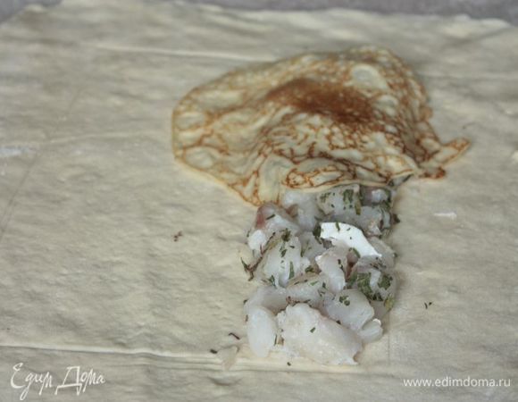 Подошедшее тесто еще раз обомните и раскатайте в прямоугольный пласт. Наметьте зону для начинки, отступив по 6-7 см с каждой стороны, не прорезая тесто. 
Выложите первую начинку, треску, вдоль длинной стороны нашего теста так, чтобы она занимала примерно четверть по ширине. Накройте ее сверху блинами внахлест.