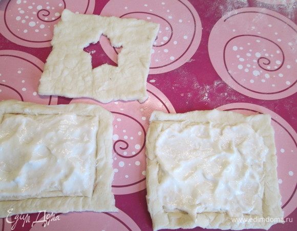 Тесто размораживаем и нарезаем квадратами. В половине из них прорезаем по центру отверстия любой формы. Смазываем половину целых квадратов соусом из хрена со сметаной.