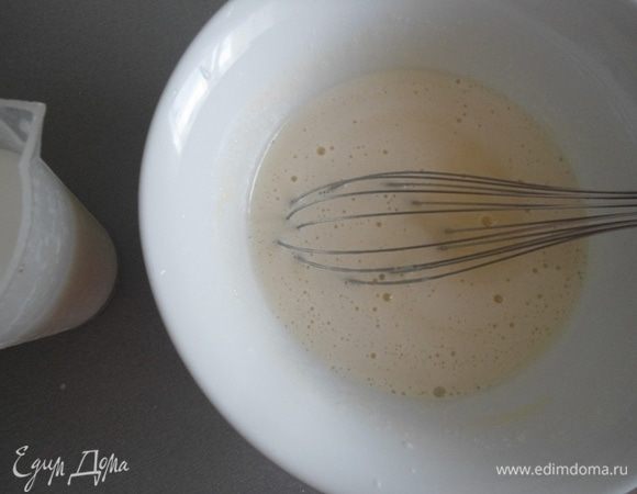 Удобнее перелить молоко в стакан с носиком. Помешивая венчиком тонкой струйкой влить молоко в яичную смесь.